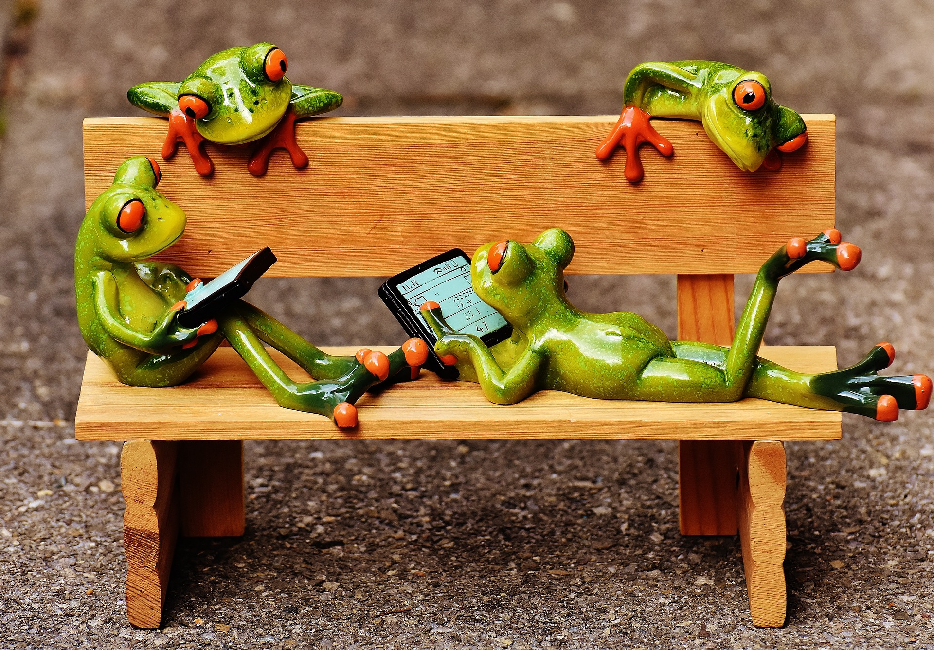 Frogs on a bench with laptops and tablet computers