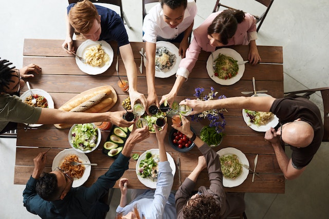 A group gathers around a dinner table, toasting each other