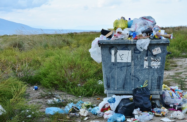 A pile of garbage atop an overfull waste bin.