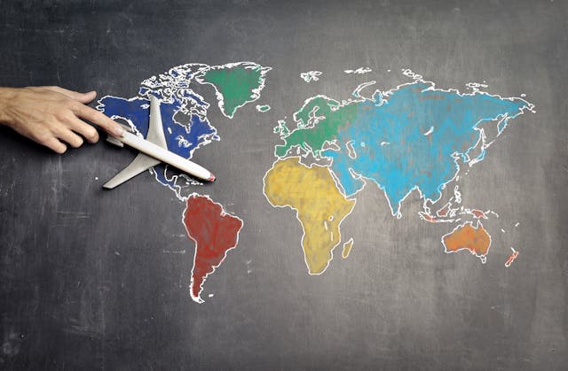 A chalk diagram of the global map, with a man pushing a model airplane across it.