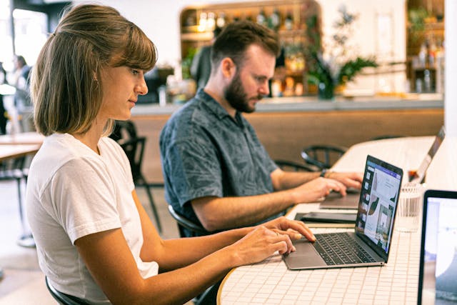 Two people sat working on laptop computers