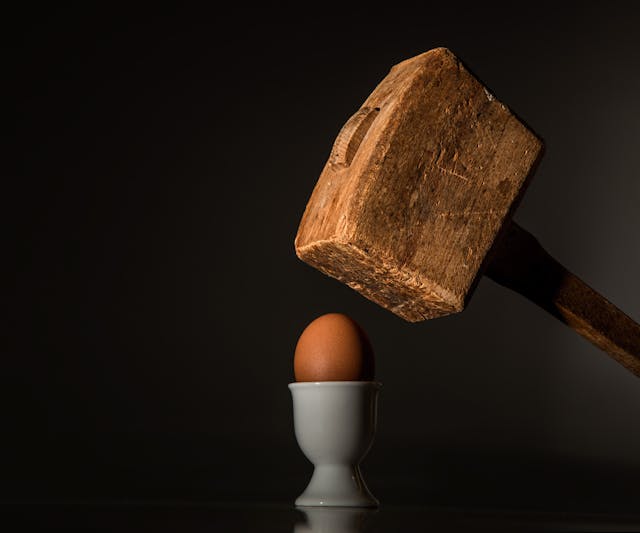 Wooden mallet about to strike an egg