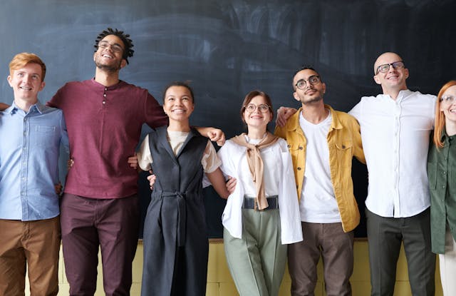A group of young adults from various cultures and nations smile as they stand in a line.