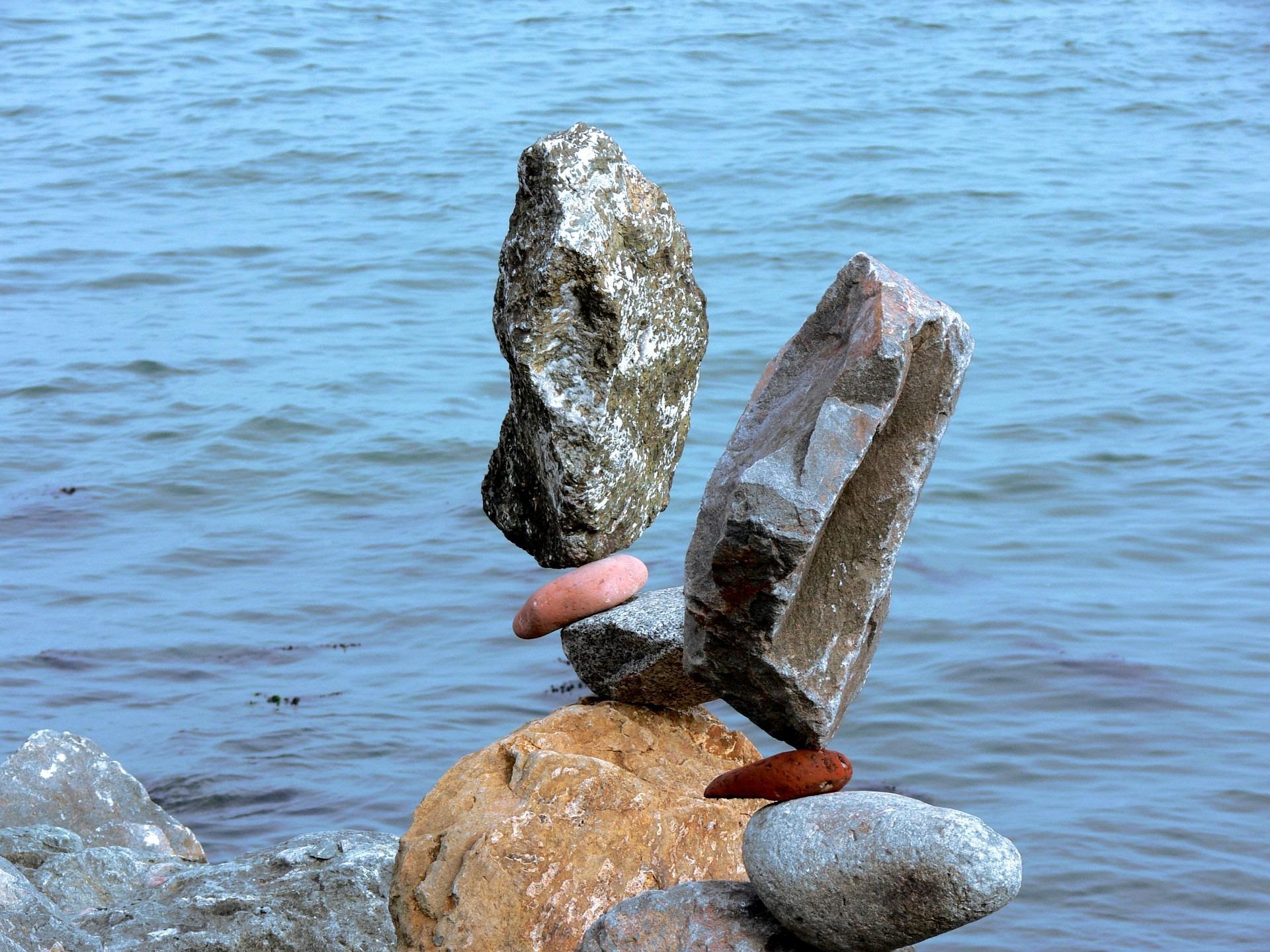 A collection of precariously stacked rocks in front of water