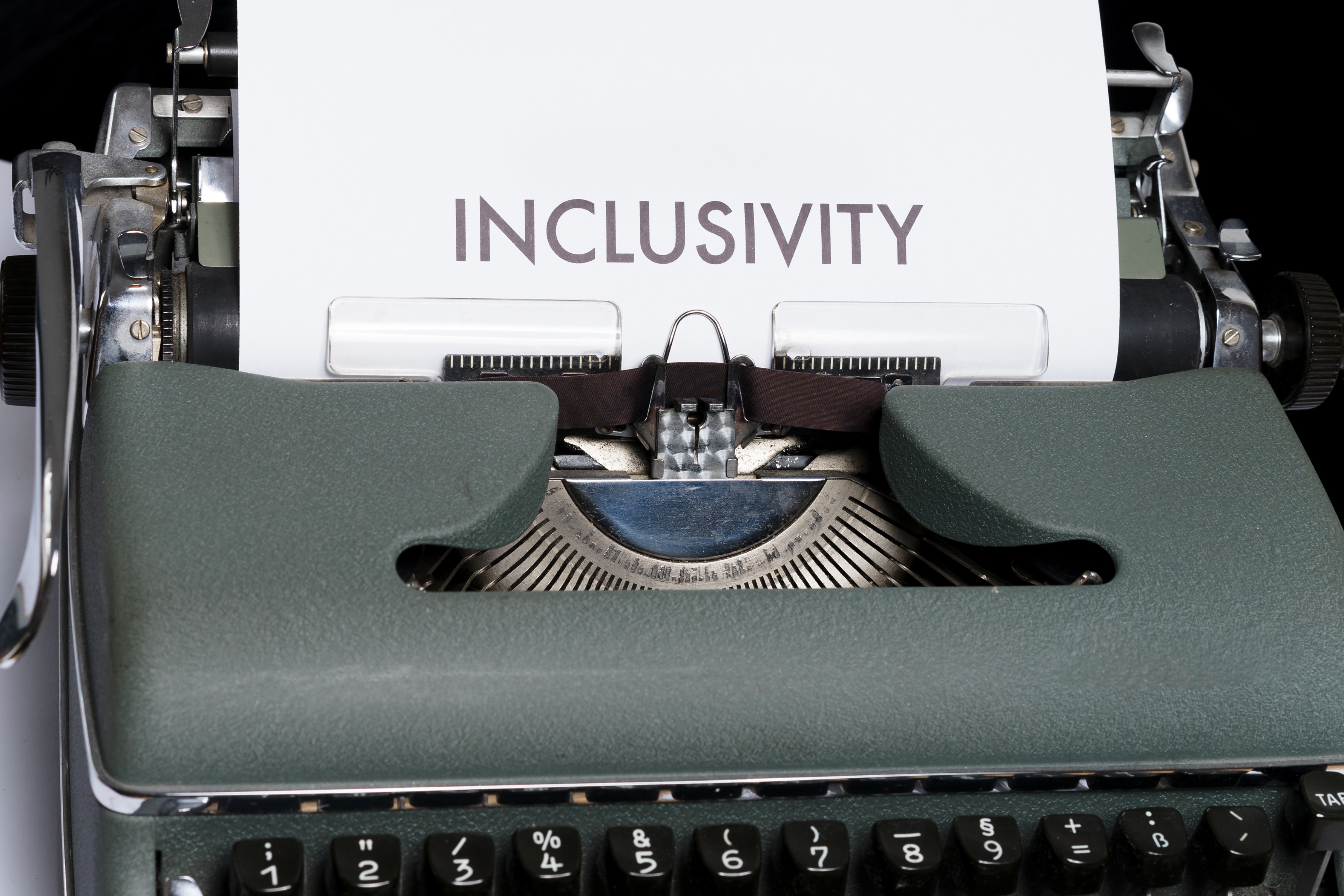 An old-fashioned typewriter that has a piece of paper with 'Inclusivity' written on it in large text