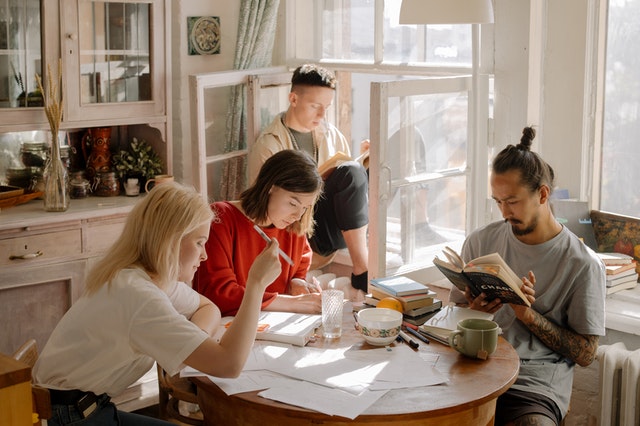 A group of young university students studying around a kitchen table.