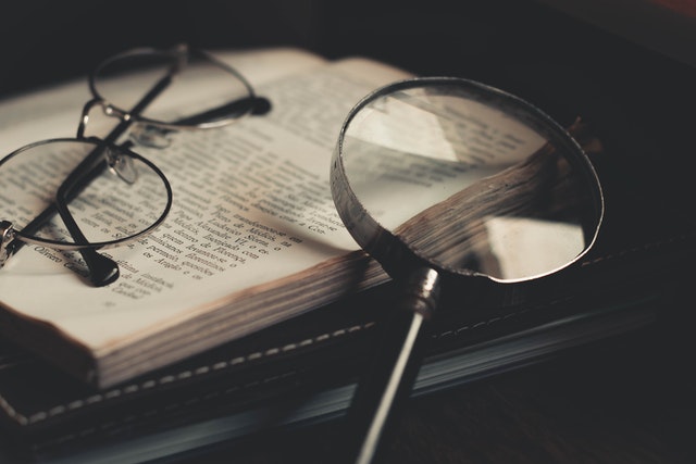 Glasses and a magnifying glass resting on an open book