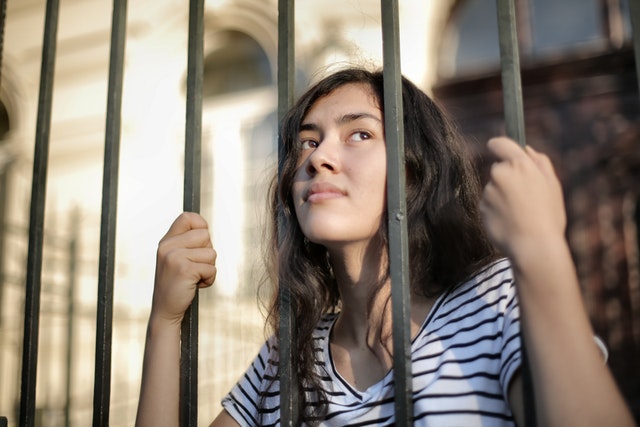 A young girl stares out from behind bars