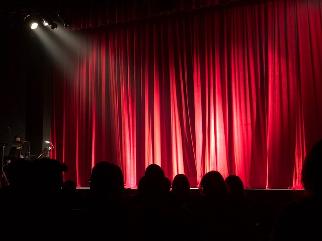 A well lit theatre stage, awaiting actors